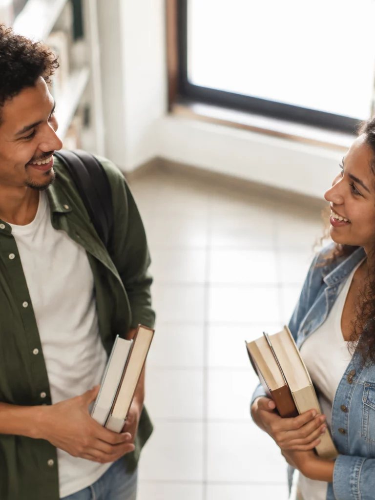 Duas participantes conversando de pé no corredor entre prateleiras de livros